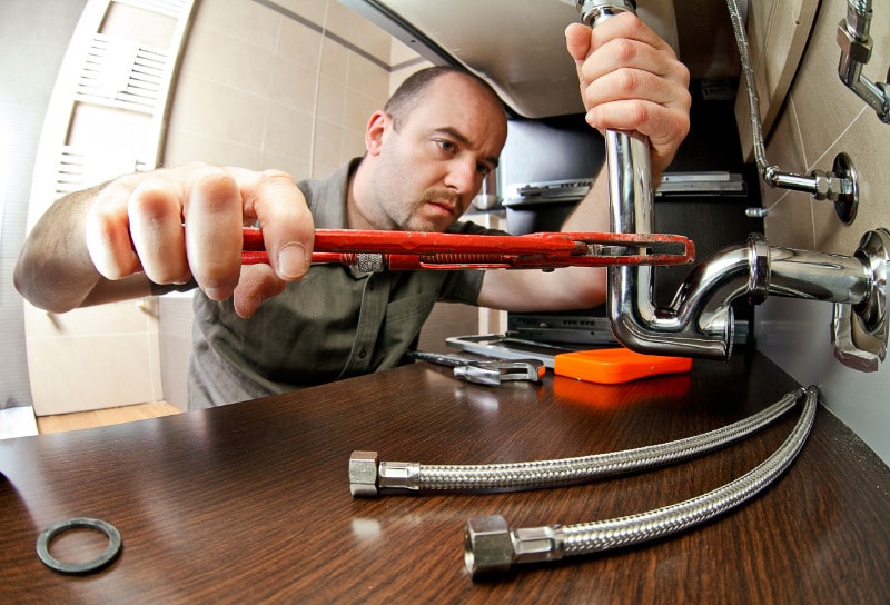 Man fixing plumbing under sink